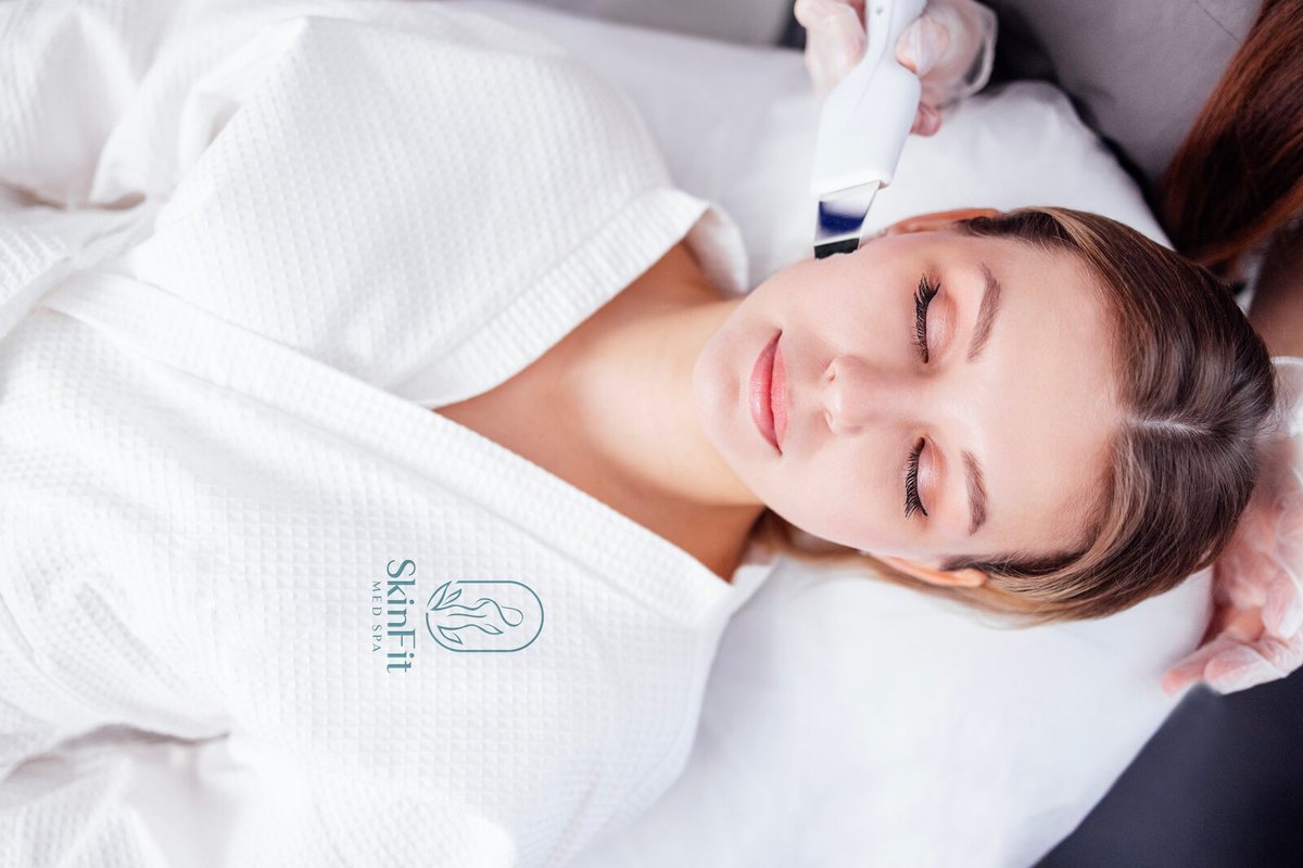Client relaxing in a branded robe during a med spa facial treatment